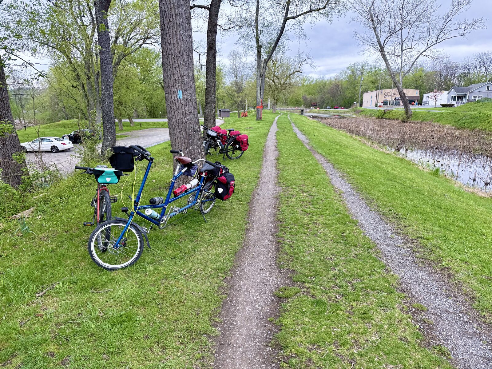The Clown Bike folding tandem, loaded for touring, parked beside a canal towpath