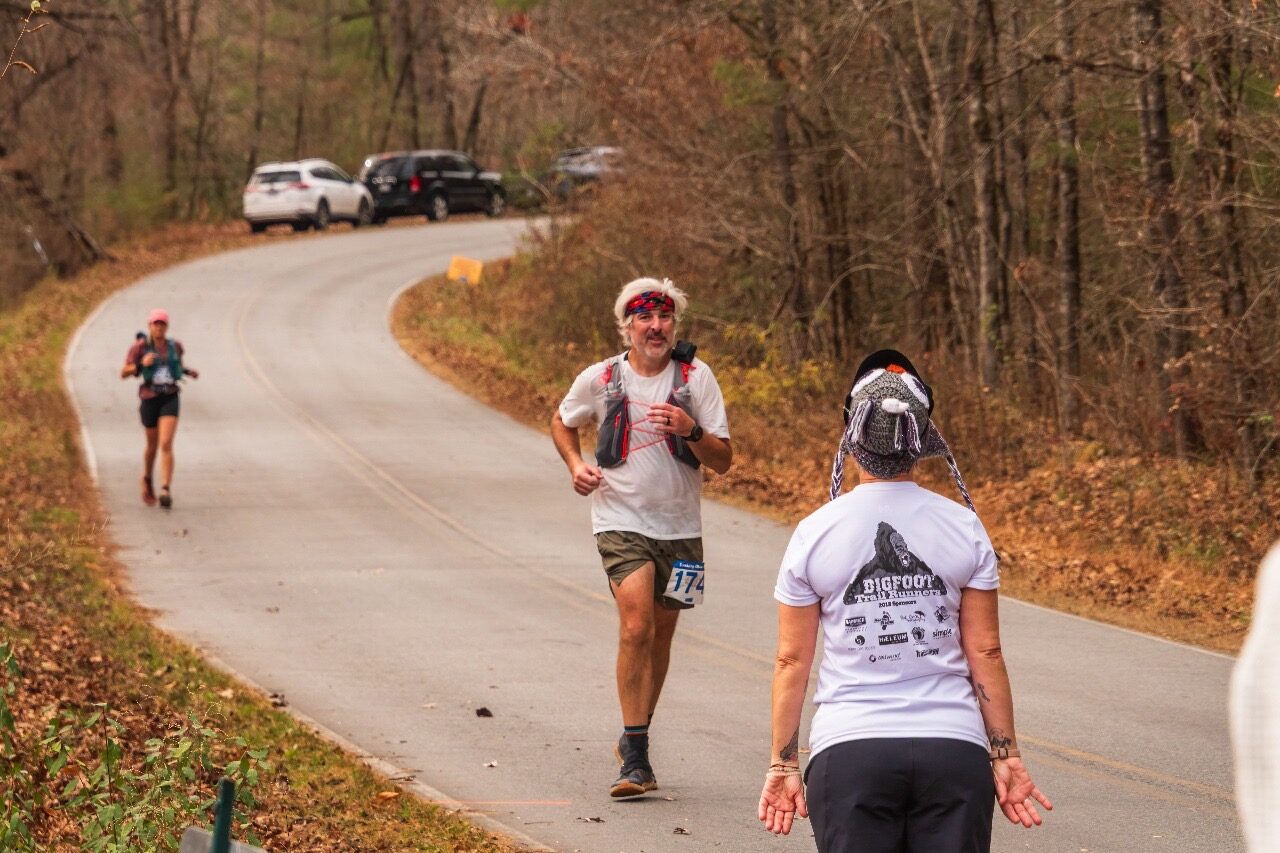 Pat running a trail ultramarathon course on a paved stretch in autumn